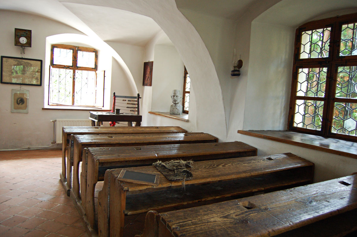 Sală de clasă pregătită pentru elevi, cu bănci și tablă